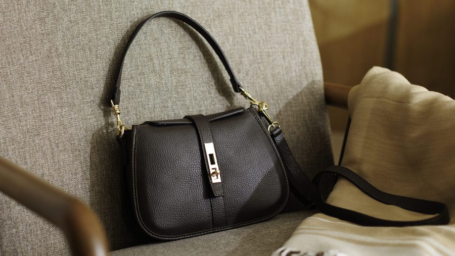 Ženske kožne torbe za leto 2026 ženska kožna crna torba na braon fotelji