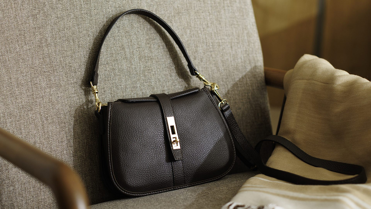 Ženske kožne torbe za leto 2026 ženska kožna crna torba na braon fotelji